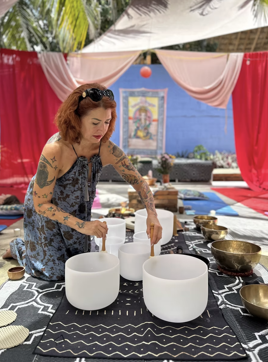 Hands playing crystal singing bowls in the Ganesha's Lounge courtyard