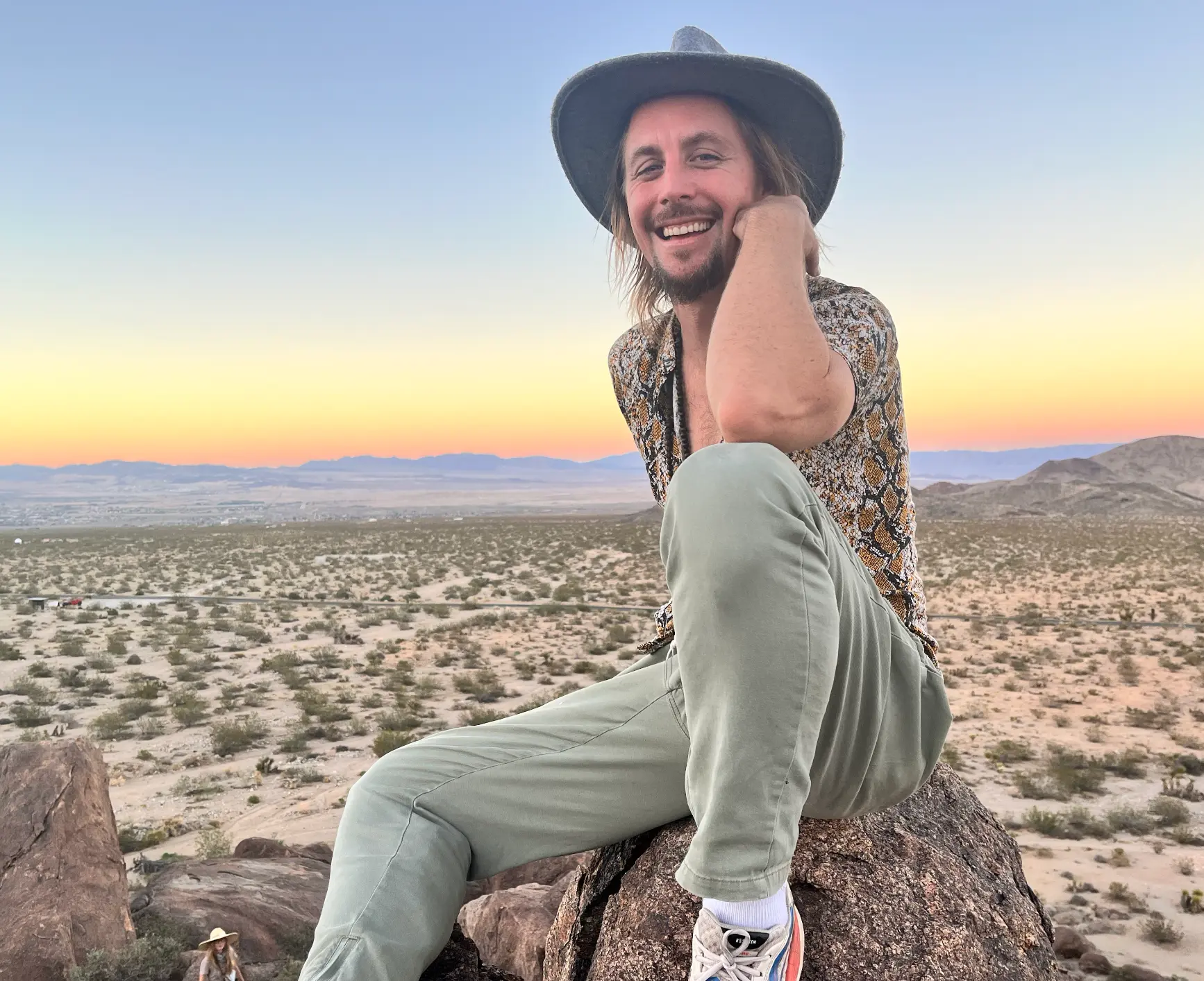 Ganesha sitting on a rock, smiling, above a desert valley at sunset