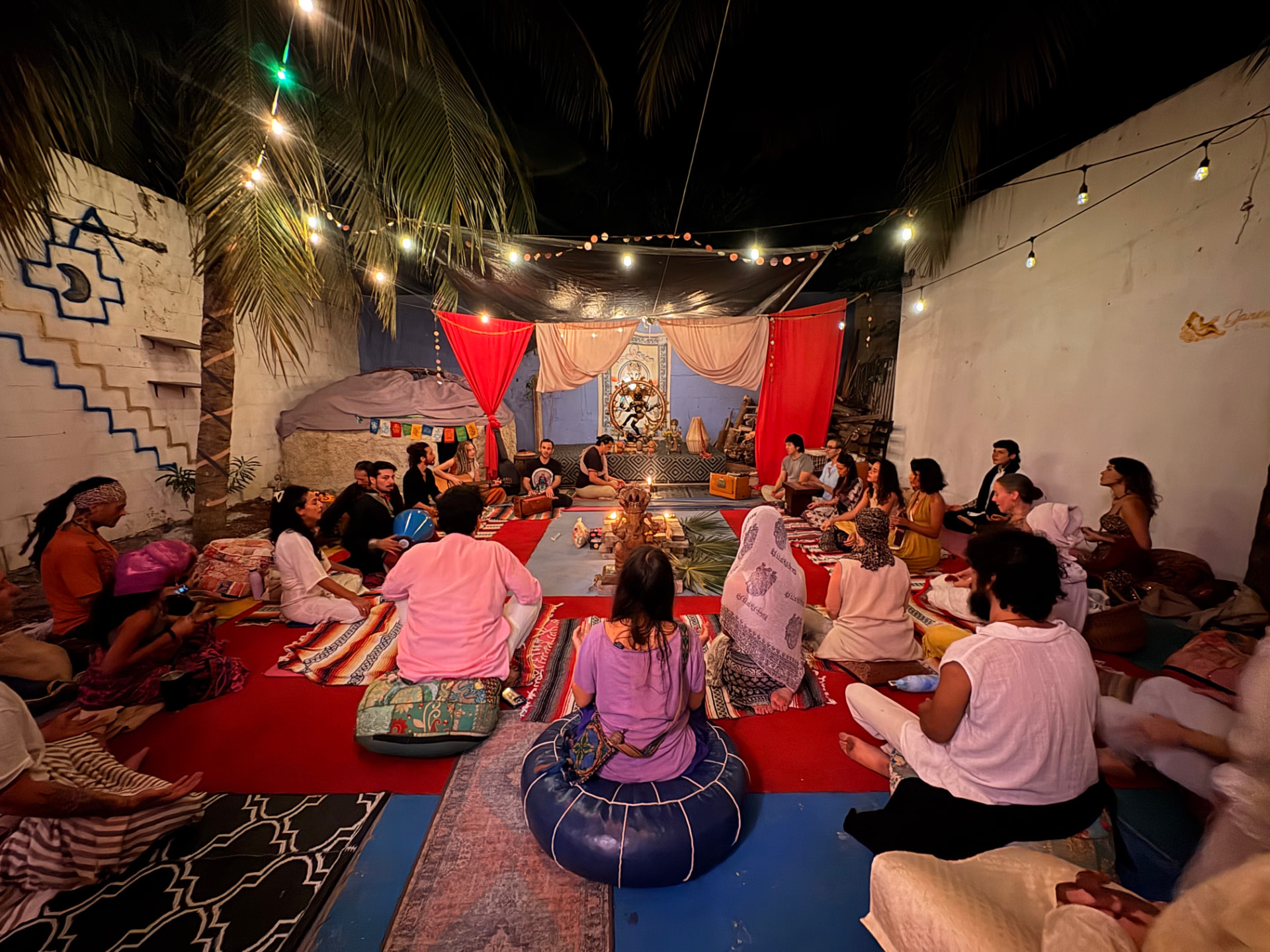 A candlelit kirtan gathering in the Ganesha's Lounge courtyard at night
