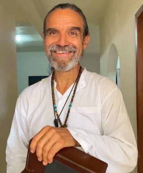 Fernando Fernandez smiling in a white shirt with beaded necklaces